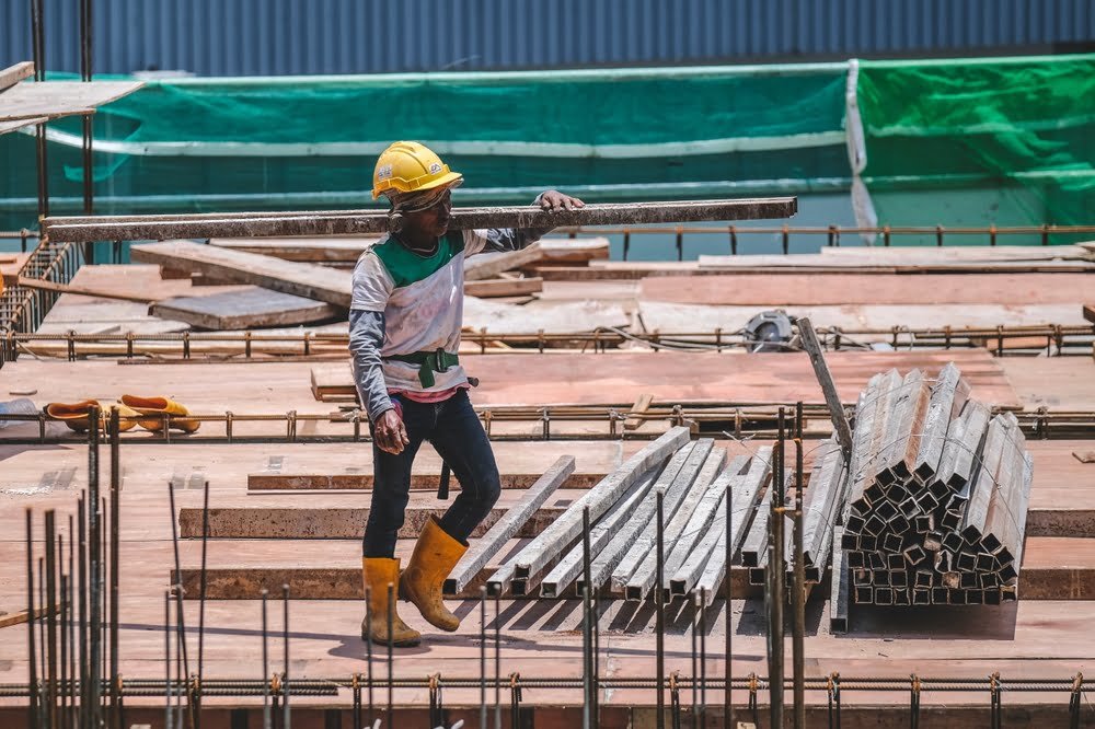 Construction workers Real Estate Development Malaysia wearing safety protective equipment while working on high-rise buildings at the construction site.