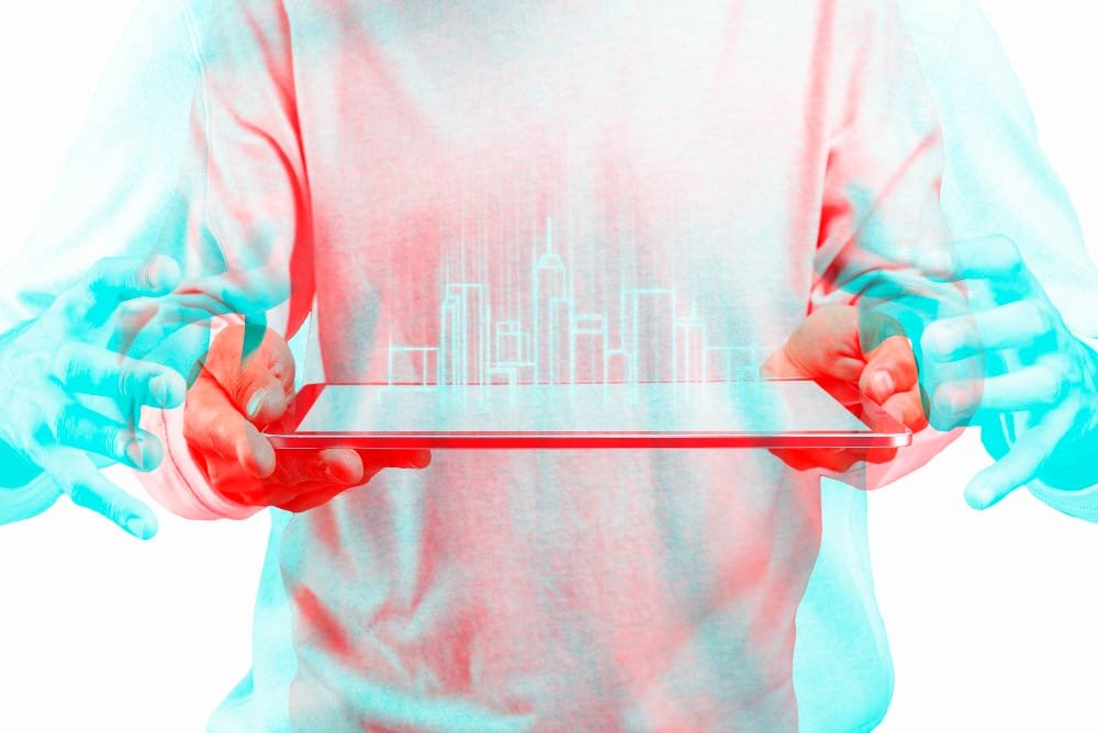 Person holding a transparent tablet displaying holographic cityscape with red and blue anaglyph effect, symbolising Construction Technology in Malaysia.