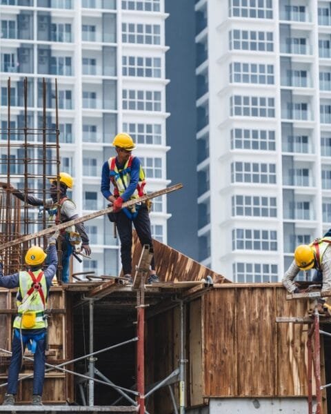 Construction workers in safety gear working on a building site, representing Malaysia Construction Labor Market shortafe.