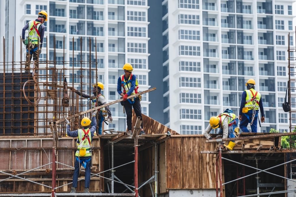 Construction workers in safety gear working on a building site, representing Malaysia Construction Labor Market shortafe.