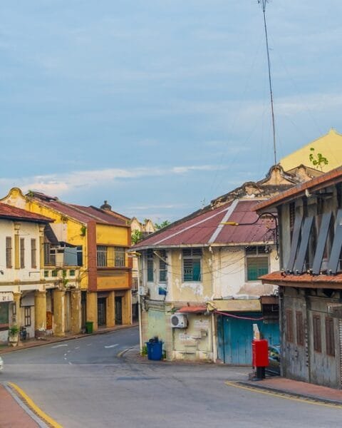 Old town street in Malacca with colorful vintage buildings and a street lamp, showing the demand for Affordable Housing Malaysia.