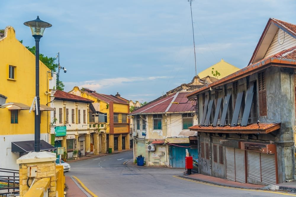 Old town street in Malacca with colorful vintage buildings and a street lamp, showing the demand for Affordable Housing Malaysia.