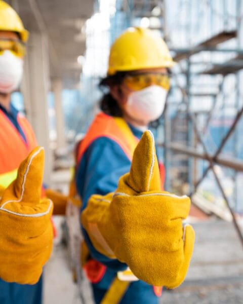 Two construction workers in safety gear giving thumbs up on a site, representing Construction Safety in Malaysia.