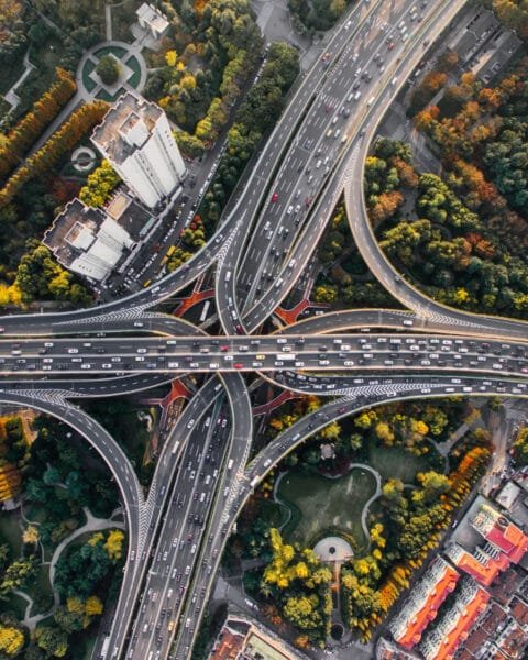 Aerial view of a multilevel interchange with heavy traffic surrounded by trees to represent Public-Private Partnerships Malaysia and future projects.