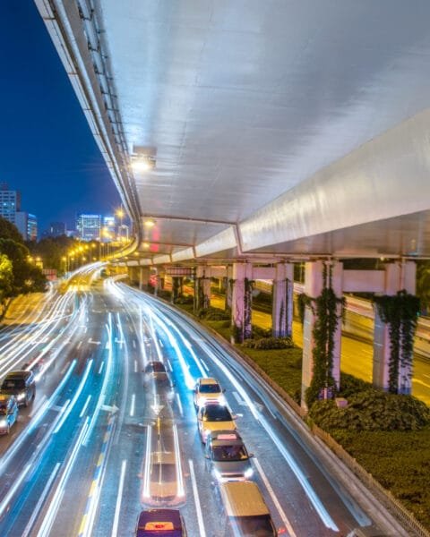 A night cityscape with light trails on a busy road under an overpass and illuminated skyscrapers in the background, representing successful PPP Projects Malaysia.