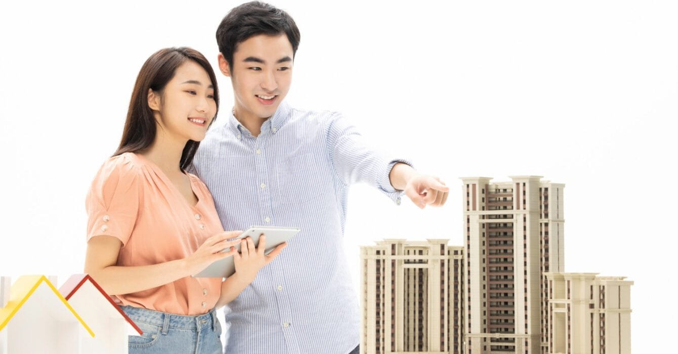 Real Estate Trends Malaysia represented by Two people with a tablet by architectural models of buildings.