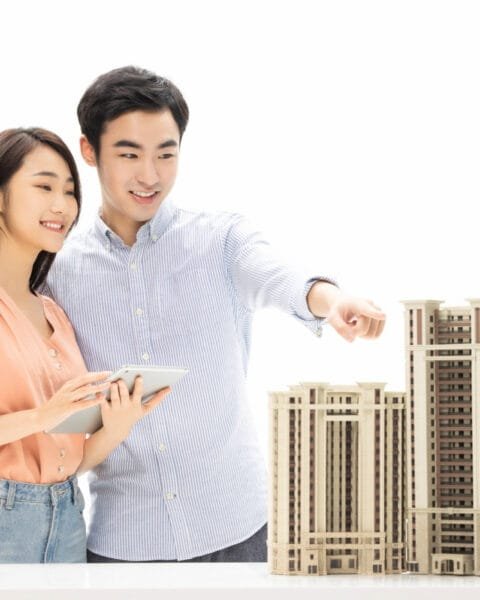 Real Estate Trends Malaysia represented by Two people with a tablet by architectural models of buildings.