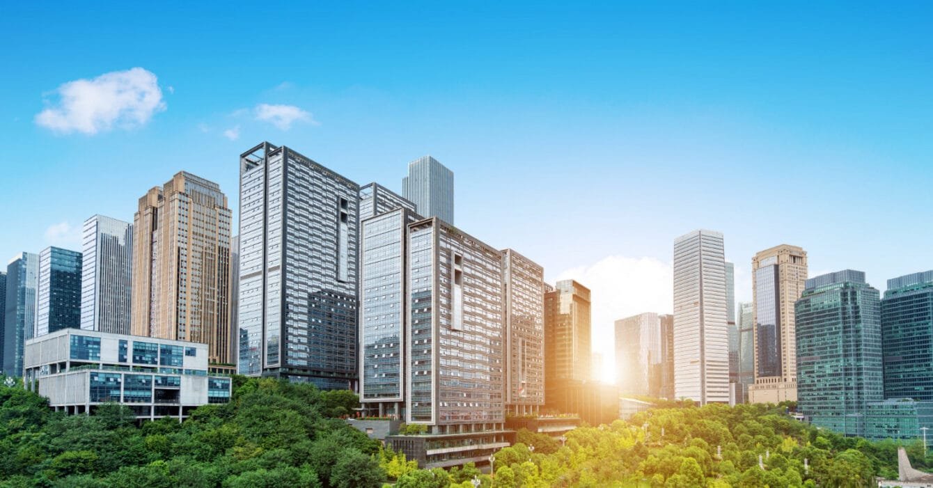 Malaysia Sustainable Materials Trends: Modern skyscrapers above green park with sunrise in city.